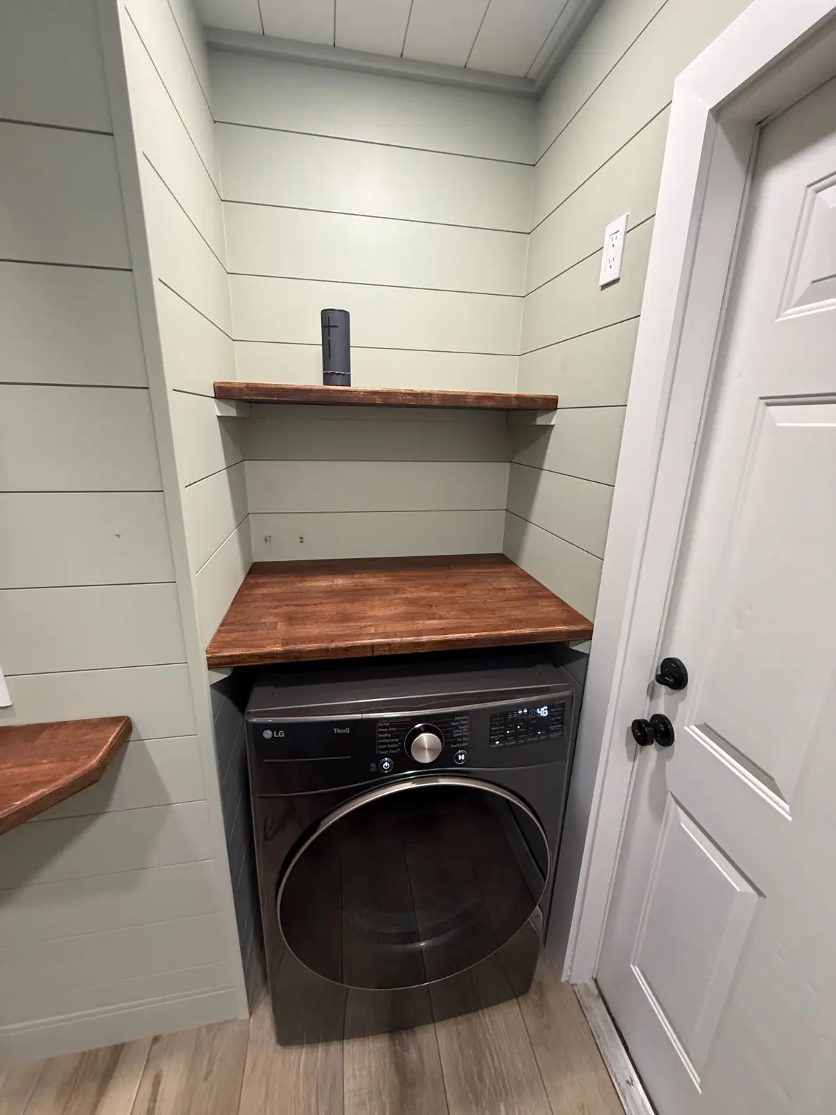 Freshly painted laundry room with sage green shiplap walls, wood shelving and washer, interior painting in Wellington, FL