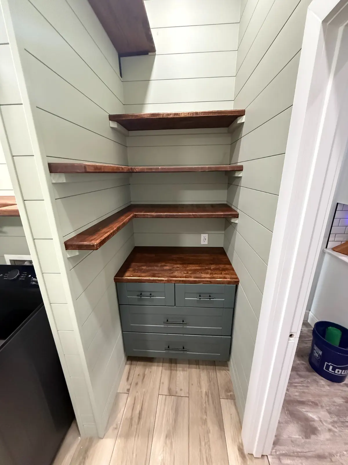 Freshly painted sage green shiplap pantry with wood shelving, painted cabinet drawers and wood countertop