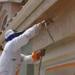 Painter applying exterior paint to a stucco home in Palm Beach County, Florida.